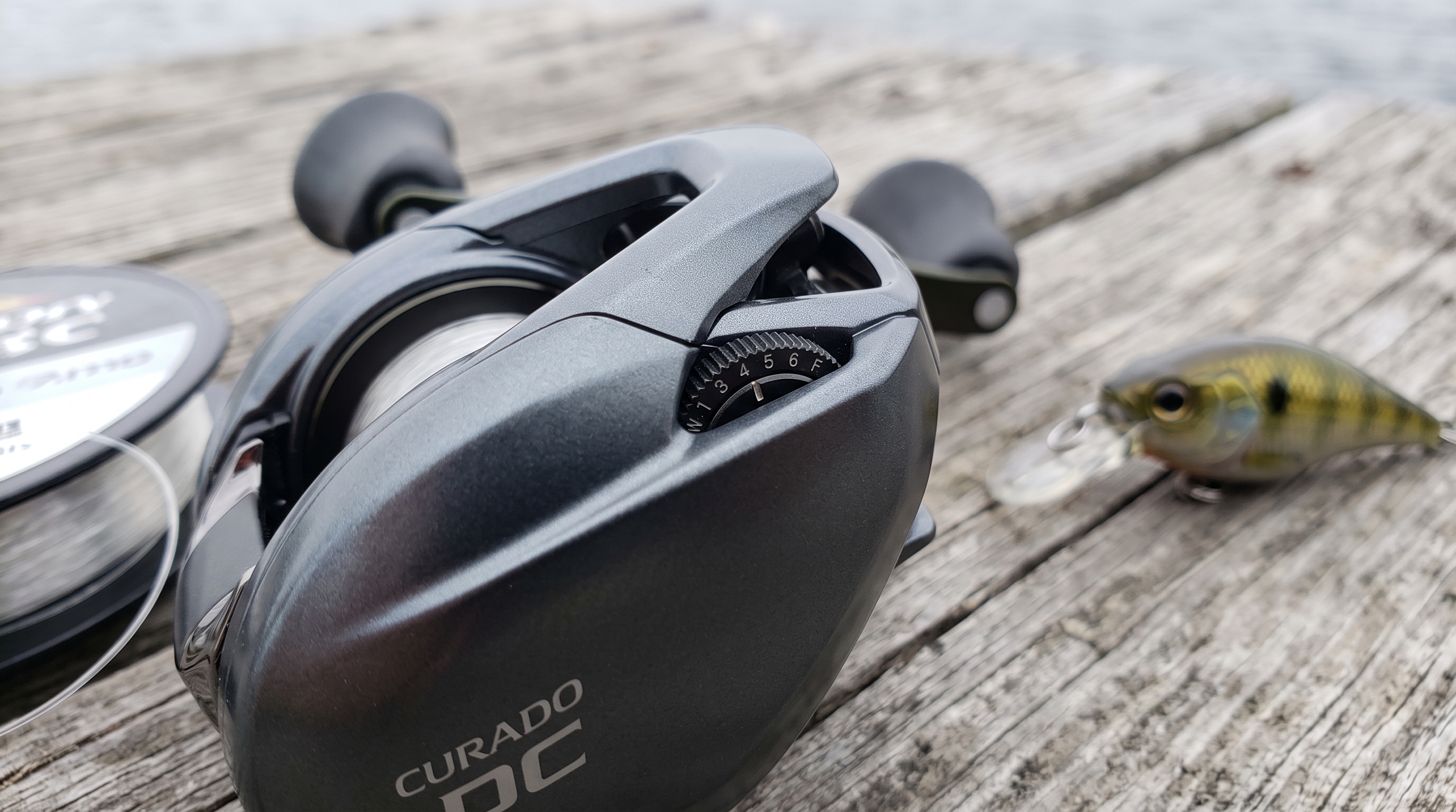 Shimano Curado DC side plate showing dialing settings next to a crankbait