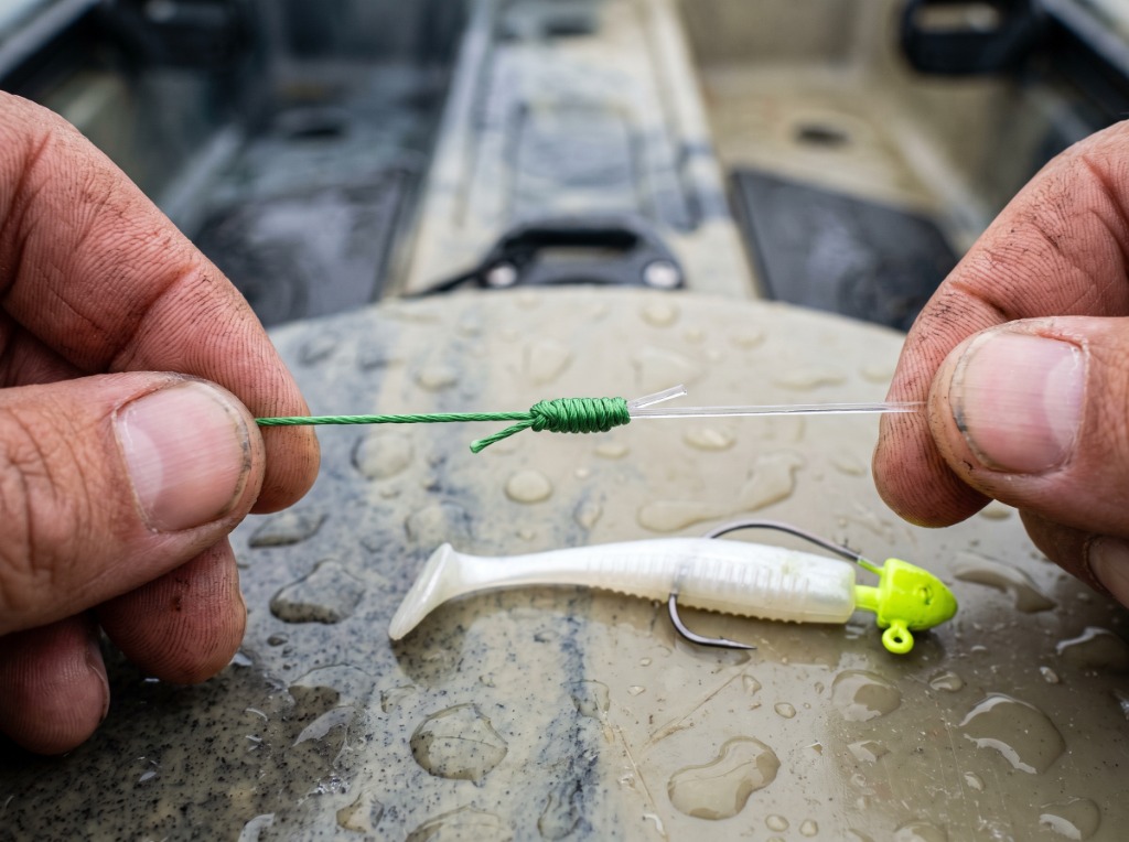 Close-up macro of an expertly tied FG knot connection between green braided line and fluorocarbon leader on a fishing kayak