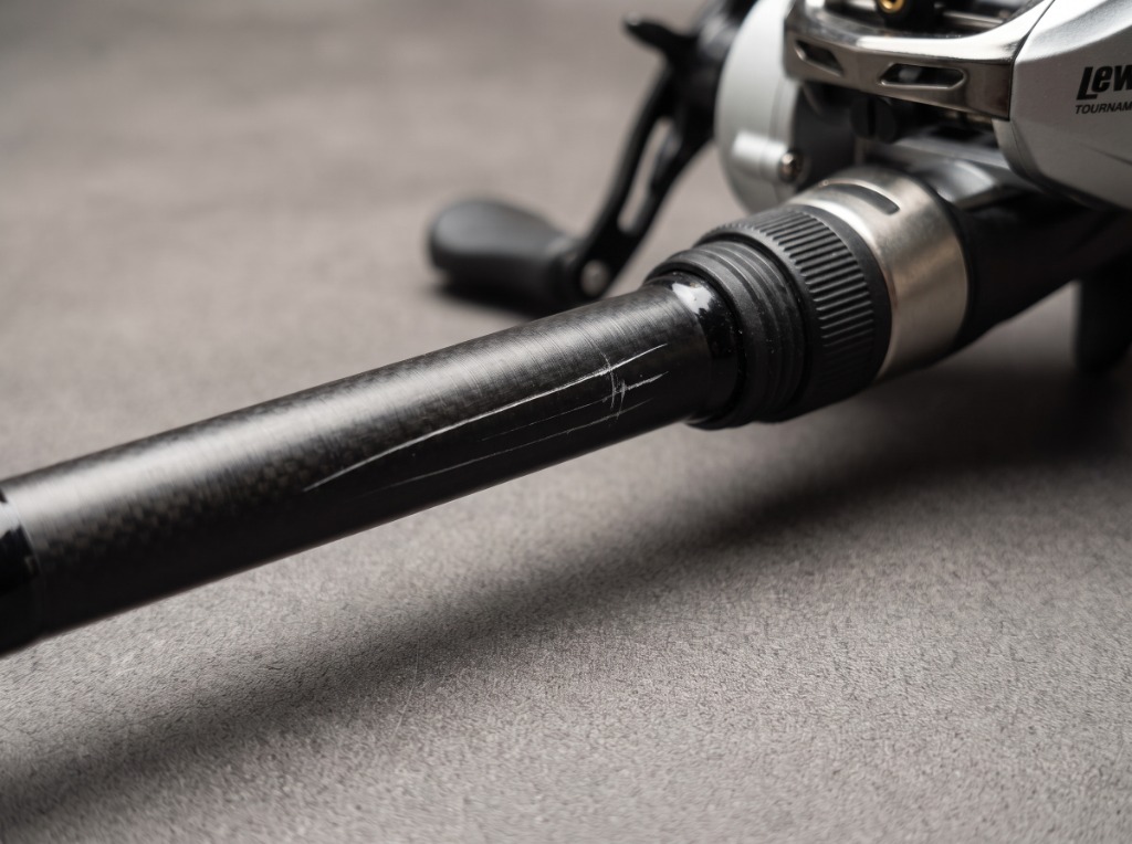 Macro close-up detail of St. Croix Legend Tournament Bass casting rod blank showing SCIV+ carbon weave, nylon body Fuji reel seat with aluminum and stainless steel locking nut assembly, and Lew's Tournament baitcasting reel
